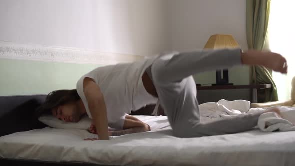 Handsome Young Guy in Pajamas Jumping Into Bed and Taking Cover with a Blanket