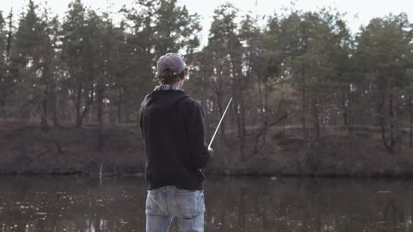 A young guy catches a predatory fish on spinning from the shore. Fishing as a hobby.