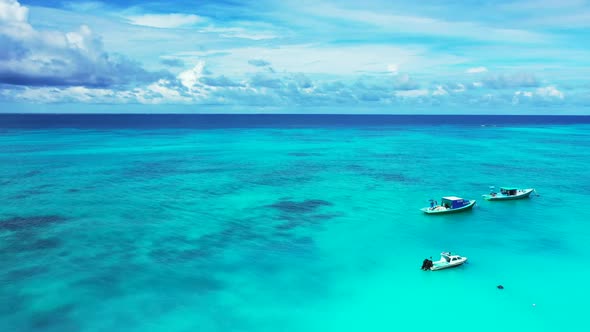 Aerial above panorama of idyllic tourist beach vacation by turquoise sea with white sand background 