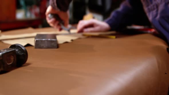 Shoemaker cutting a piece of leather