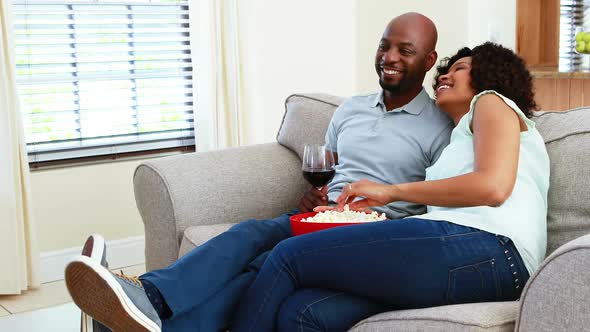 Couple having snacks while watching television in living room 