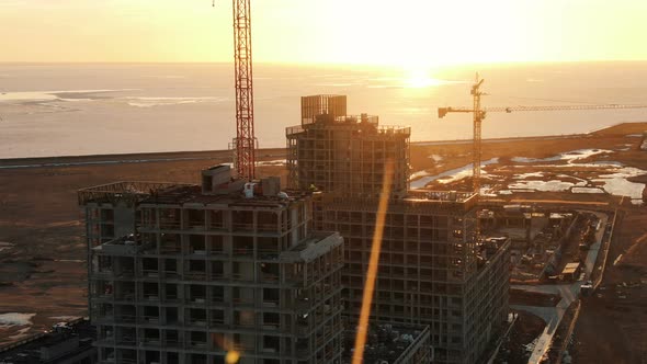 Shooting From a Drone Under Construction Multi-storey Building Against the Sunset, the Builders Walk