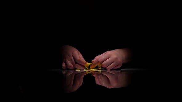 Person Makes Yellow Origami. Black. Closeup