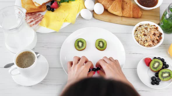 Playful Woman Having Fun Making Smiling Face on Plate Using Fresh Fruit and Berry Top View