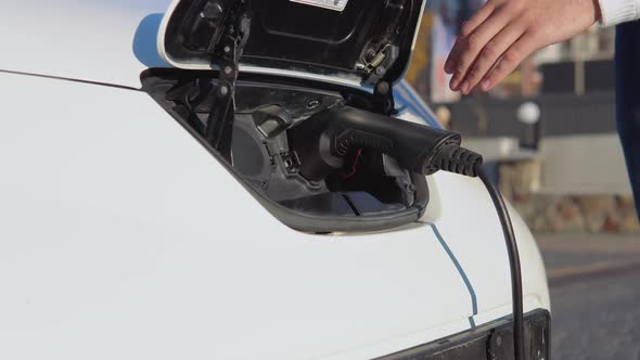 A Fairskinned Male Driver Disconnects the Electric Car From the Power System