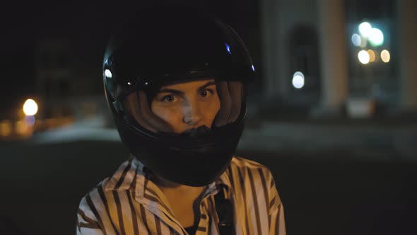 Portrait of Beautiful Young Woman Motorcyclist in Black Motorcycle Helmet in the Night Street