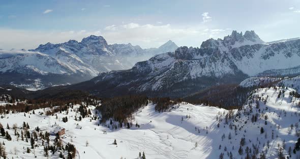 Backward Aerial to Snowy Alpine Valley with Woods Forest at Cinque Torri