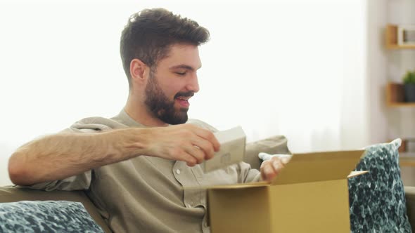 Happy Man Opening Parcel Box at Home