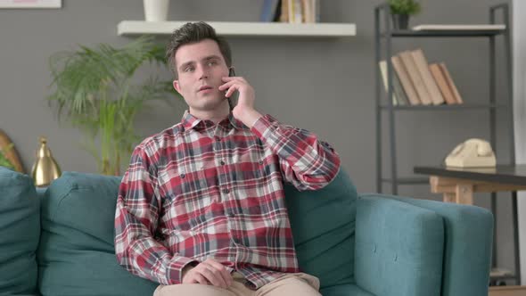 Man Talking on Smartphone on Sofa