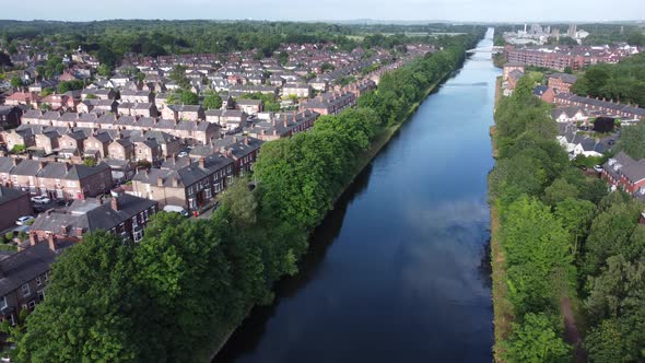 Aerial view flying above wealthy Cheshire housing estate alongside Manchester ship canal rising forw