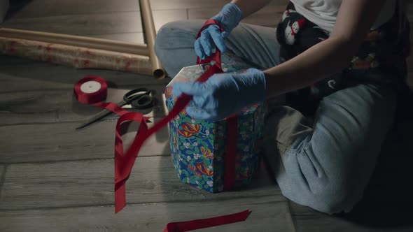 Woman Hands in Protective Gloves Packing Christmas Gifts