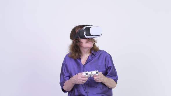 Happy Senior Man Playing Games While Using Virtual Reality Headset