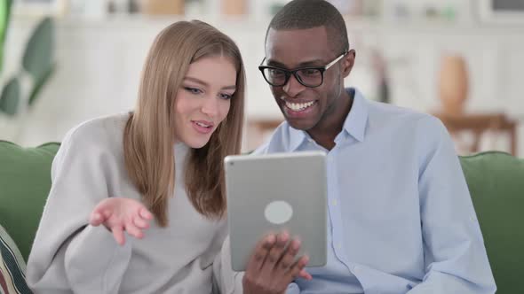 Online Video Chat on Tablet By Mixed Race Couple Home