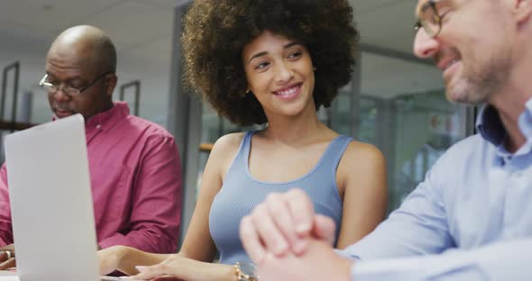 Diverse male and female business colleagues smiling and using laptop