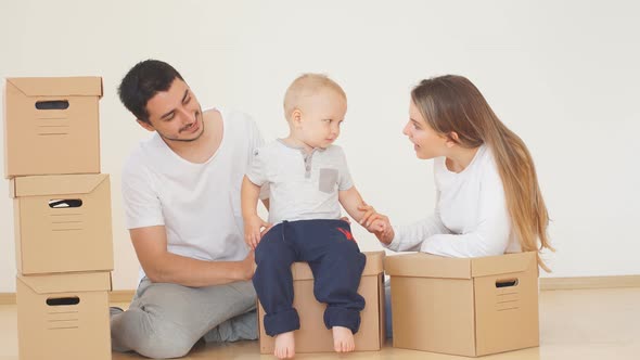 Family with Boy Unpacking Moving Cardboard Boxes at New Home