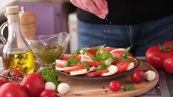 Salting Caprese Salad  Mozzarella Cheese Balls Sliced Cherry Tomatoes and Basil