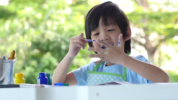 Cute Asian Child Enjoying Arts And Crafts Painting With His Hand