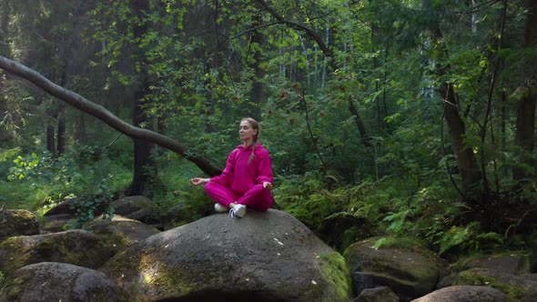 A Girl Sits on a Rock and Meditates in the Forest