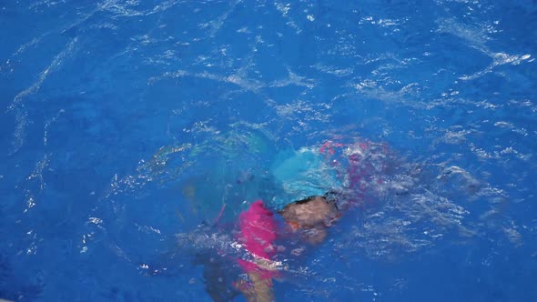 Small Child Girl is Learning to Swim in Pool Diving and Floating in Water