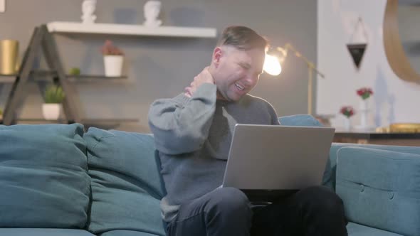 Casual Man with Laptop Having Neck Pain on Sofa