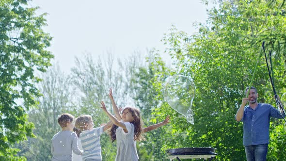 Children Enjoying Catching Giant Bubbles during Outdoor Performance