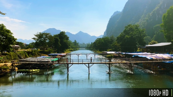 People Walking Across a Bamboo Bridge in the Mountainous Countryside of Vang Vieng, Laos