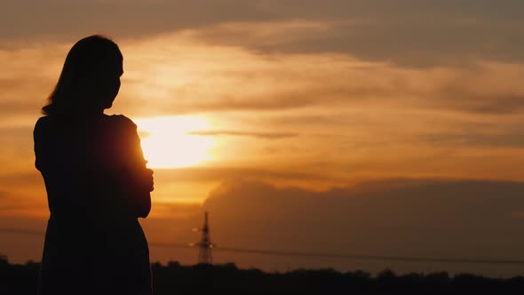 The Lone Silhouette of a Woman at Sunset Staring Into the Distance