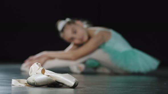 Unfocused Blurry Girl Artist Dancer Tired Child Ballerina Sitting on Floor After Dance Stretches Leg