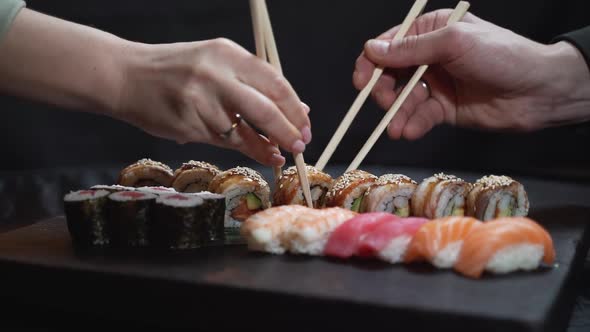 Man and woman pick up sushi with chopsticks at the same time