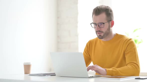 Man Celebrating Success While Using Laptop in Office