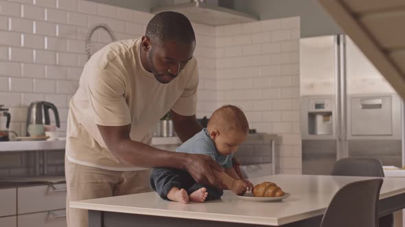 Dad Helping Son Sitting on Table