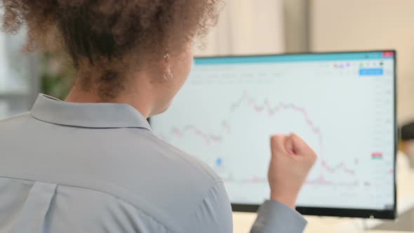 Rear View of African Woman Having Loss While Reading Charts on Desktop