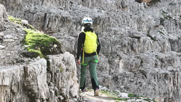 Female mountaineer with climbing gear in the Dolomites walking on a path. Close shoot.