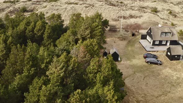 House in the Middle of Meadow Alongside Forest with Tall Trees