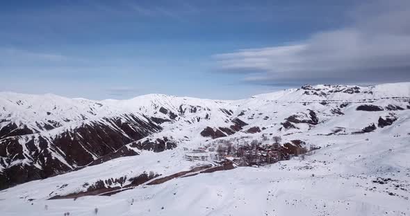 Beautiful little village in the middle of mountains in winter full of snow in highlands. cloudy sky