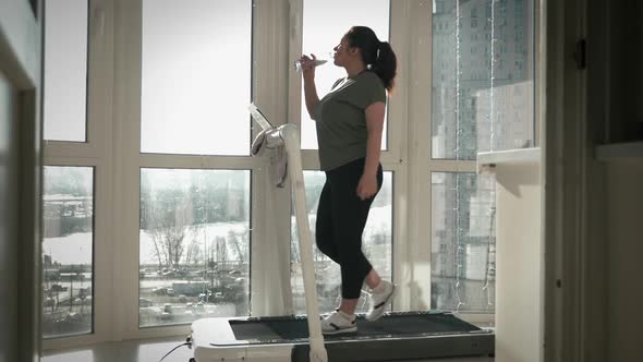 Woman drinks water on treadmill