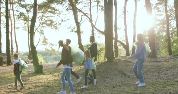 Active Diverse Volunteers with Rubbish Bags Leaving the Park After Autumn Cleanup