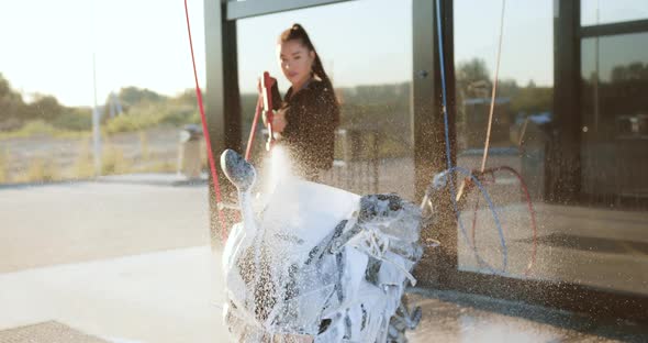 Female Motorcyclist in Black Clothes which Washing Sporty Modern Iron Horse with Foam