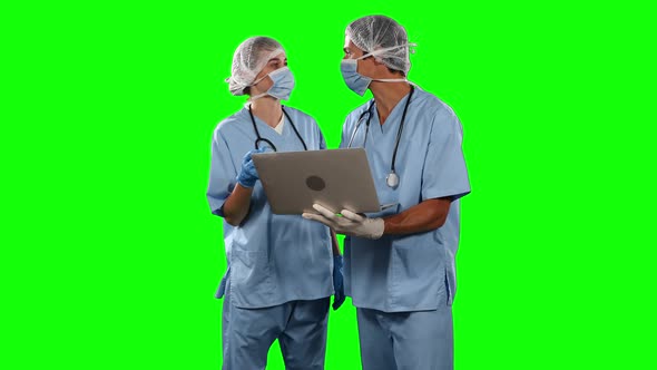 Front view of doctors watching some results on laptop with green screen