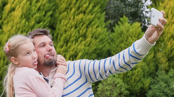 Smiling father and daughter making funny faces while taking selfie 4K 4k