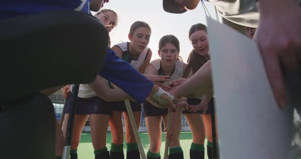 Female hockey players forming hand stack on the field