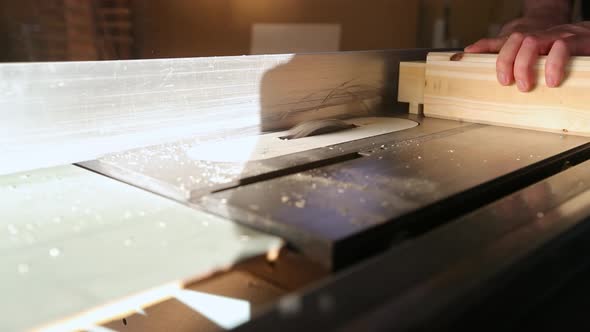 A woodworker rotates a piece of wood and pushes it over a table saw with multiple passes to make ten