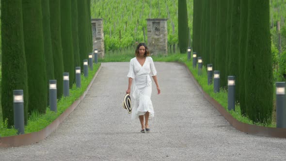 A woman walking on a path with cypress trees while traveling at a luxury resort in Italy, Europe.