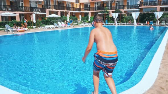 Boy Jumping in Swimming Pool at Sunny Day alt