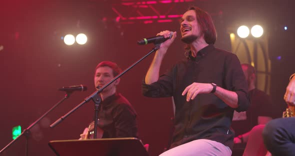 Men Singing to Microphone on Light Background