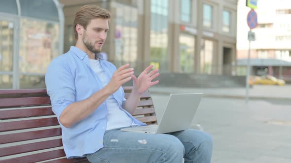 Man Talking on Video Call While Sitting Outdoor on Bench