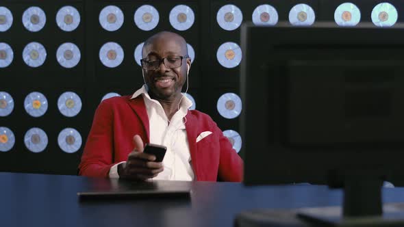 Active Africanamerican Man at Desktop Listens to Music Via Headset and Moves