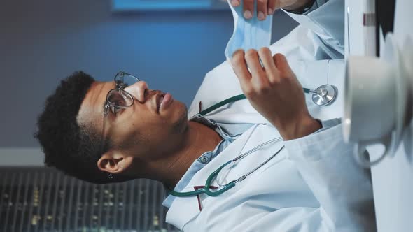 Medium Shot of Young African Doctor Showing How To Wear Medical Mask By Video Call on Computer