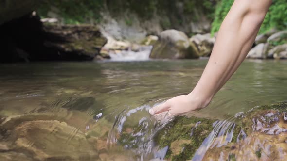 A hand in flowing stream water. Elegant and clean. Slow motion.