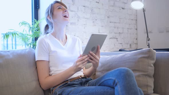 Reaction to Success by Woman Using Tablet in Bedroom